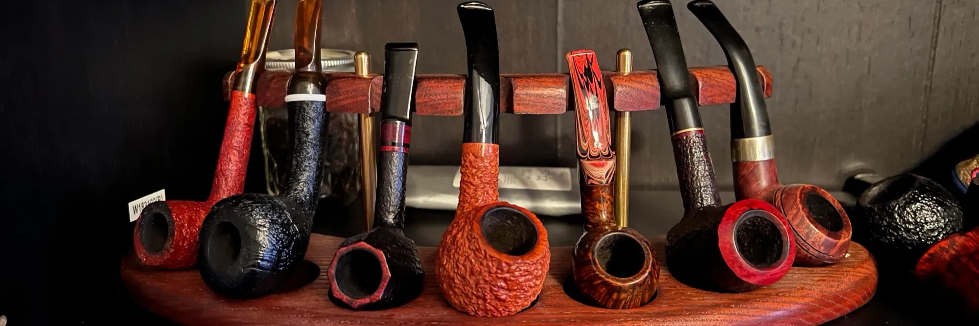 A rack of briar pipes on a wooden stand, set on a bookshelf